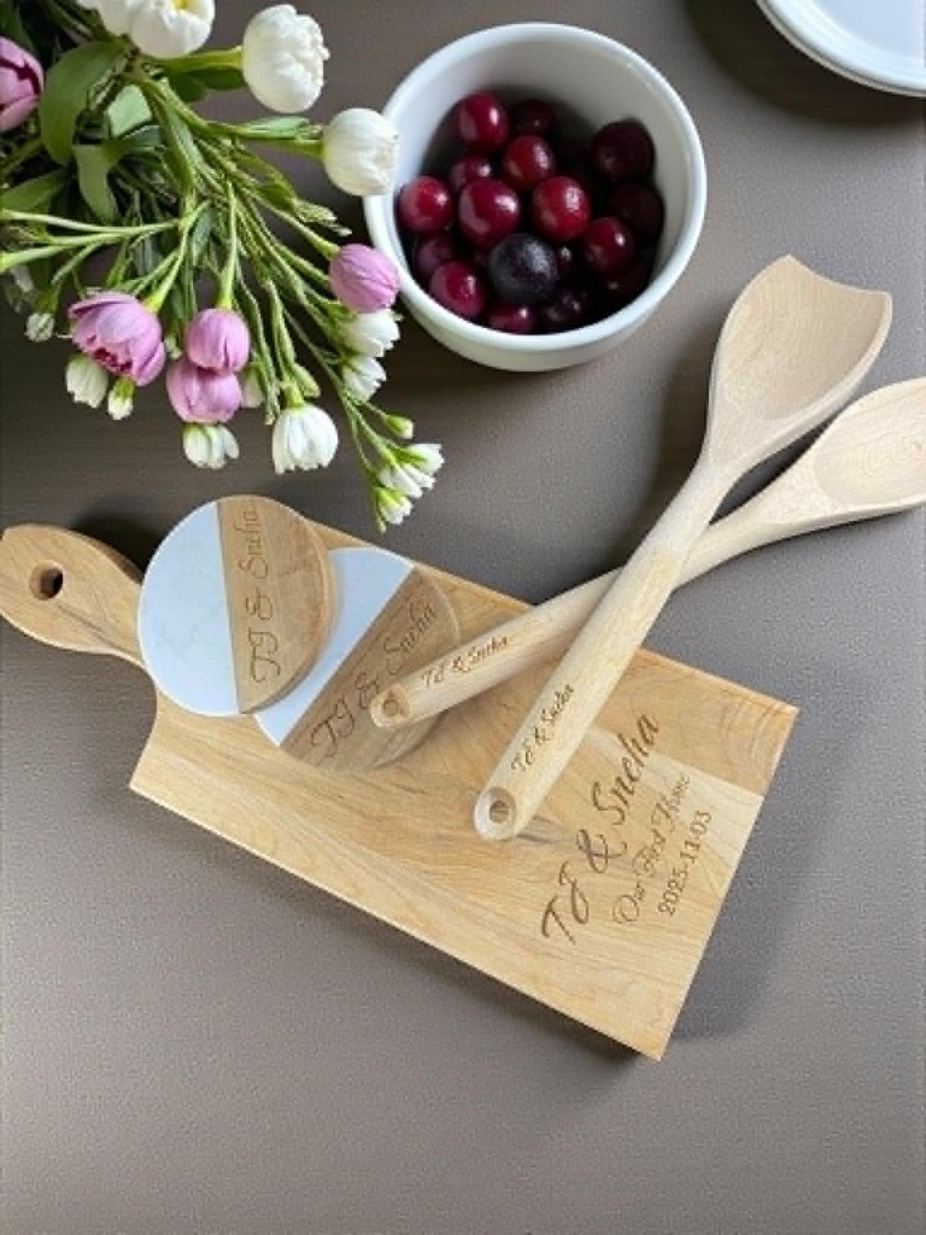 Engraved board, coasters and serving utensils laid out with flowers